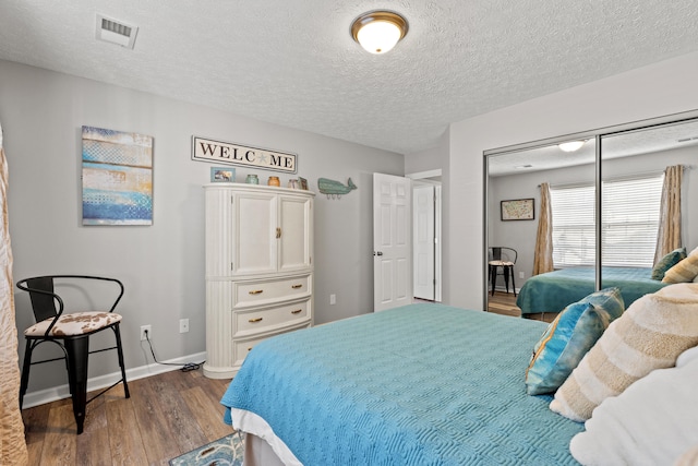 bedroom with dark hardwood / wood-style flooring, a closet, and a textured ceiling