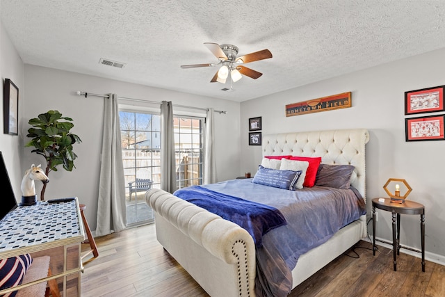 bedroom featuring a textured ceiling, dark wood-type flooring, ceiling fan, and access to outside