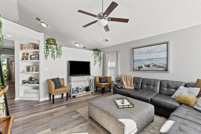 living room featuring vaulted ceiling, wood-type flooring, built in features, and a textured ceiling