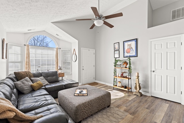 living room with wood-type flooring, high vaulted ceiling, ceiling fan, and a textured ceiling