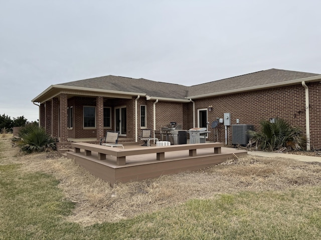 back of property featuring a deck, central AC unit, and a lawn