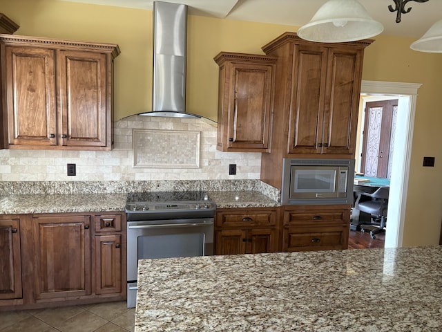 kitchen featuring appliances with stainless steel finishes, light stone counters, light tile patterned flooring, decorative backsplash, and wall chimney exhaust hood