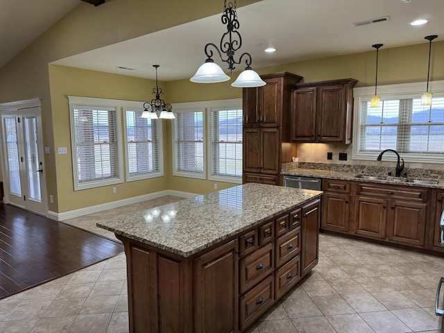 kitchen featuring pendant lighting, light stone counters, sink, and a kitchen island