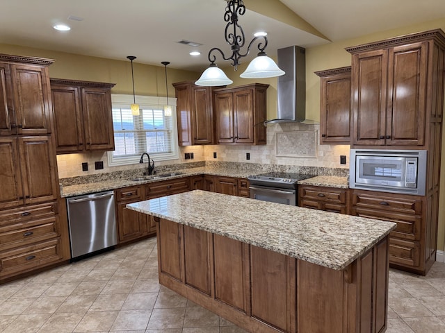 kitchen featuring pendant lighting, appliances with stainless steel finishes, wall chimney exhaust hood, and sink