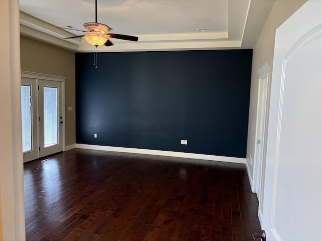 spare room with ceiling fan, dark hardwood / wood-style floors, and a raised ceiling