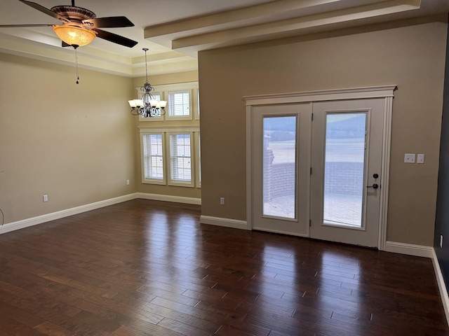 spare room with dark hardwood / wood-style floors, ceiling fan with notable chandelier, and a tray ceiling