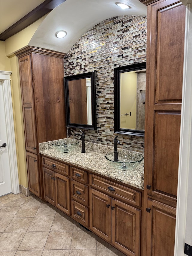 bathroom with vanity, backsplash, vaulted ceiling, and tile patterned floors