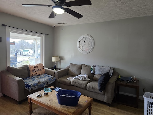 living room with ceiling fan, wood-type flooring, and a textured ceiling