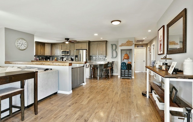 kitchen featuring a breakfast bar, a kitchen island, stainless steel appliances, light hardwood / wood-style floors, and decorative backsplash