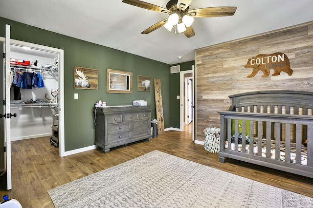 bedroom featuring a spacious closet, wood-type flooring, a closet, and ceiling fan