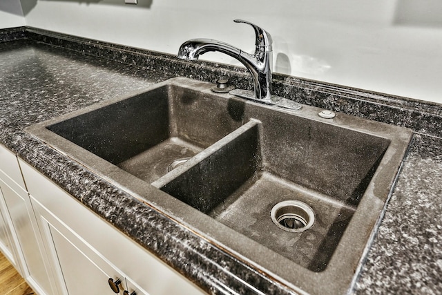 room details with white cabinetry, sink, and dark stone counters