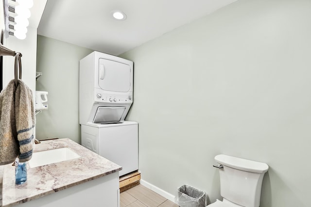 bathroom featuring stacked washer / dryer, vanity, and toilet