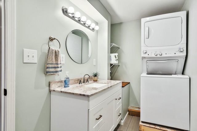 bathroom featuring vanity, stacked washer / drying machine, and hardwood / wood-style flooring