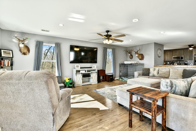 living room with ceiling fan and light hardwood / wood-style flooring