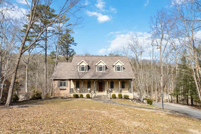 cape cod-style house with a front yard and covered porch