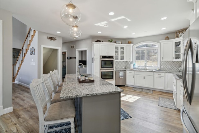 kitchen with white cabinetry, appliances with stainless steel finishes, a kitchen island with sink, and a breakfast bar area