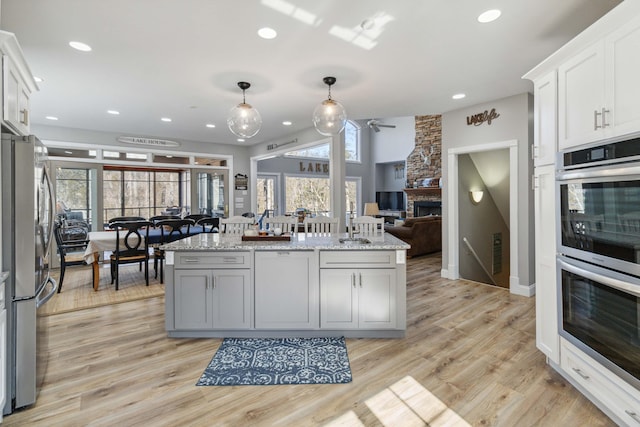 kitchen featuring white cabinetry, light stone countertops, pendant lighting, and stainless steel appliances