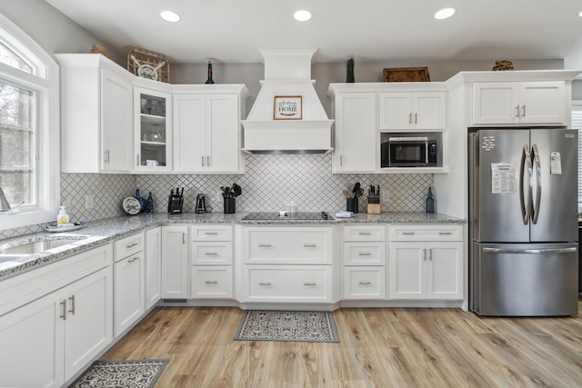 kitchen featuring stainless steel refrigerator, white cabinetry, black electric cooktop, built in microwave, and custom exhaust hood