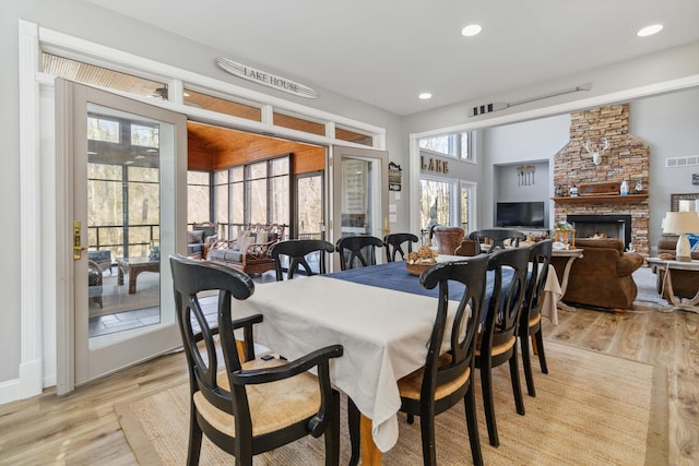 dining area with vaulted ceiling, a fireplace, and light hardwood / wood-style floors