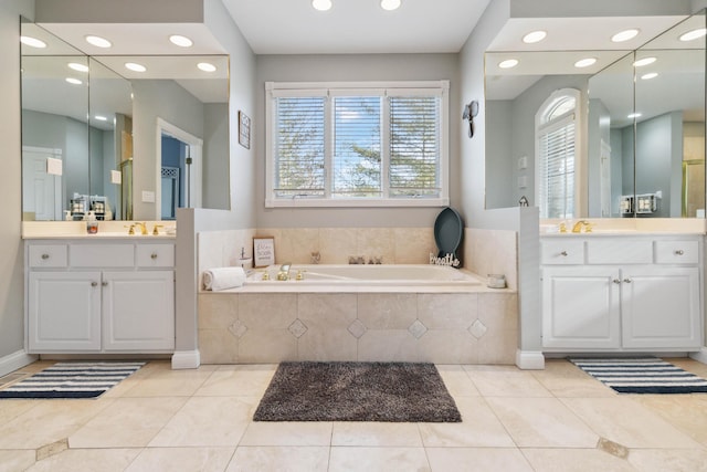 bathroom featuring a relaxing tiled tub, tile patterned floors, and vanity