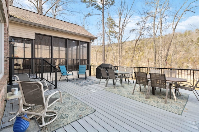 wooden deck with a sunroom and area for grilling