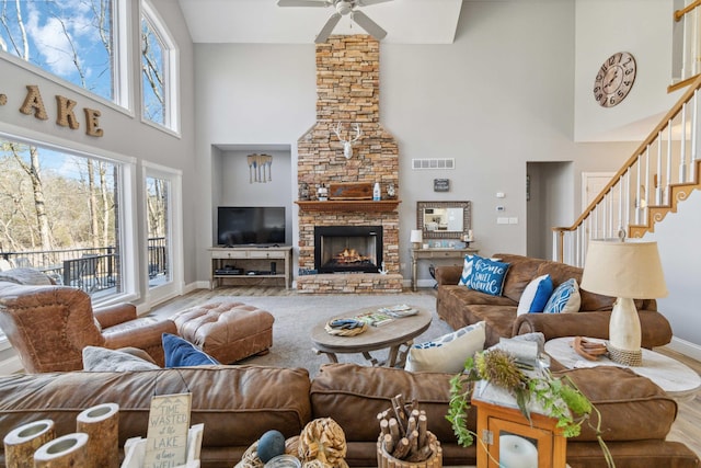 living room featuring hardwood / wood-style flooring, ceiling fan, a towering ceiling, and a fireplace