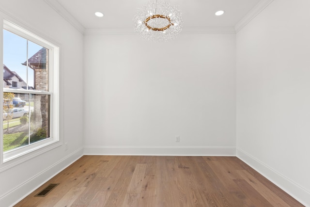 spare room featuring crown molding, wood-type flooring, a chandelier, and a healthy amount of sunlight