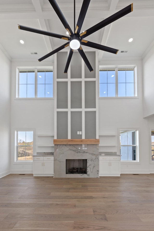 unfurnished living room featuring a high end fireplace, built in features, and light wood-type flooring