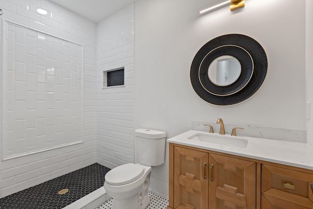 bathroom with vanity, a tile shower, and toilet