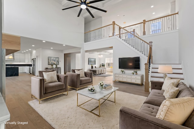 living room with wood-type flooring, a towering ceiling, and ceiling fan