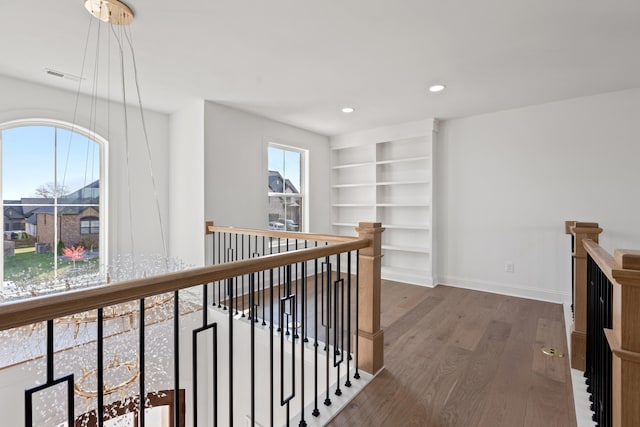 corridor with dark wood-type flooring and built in shelves