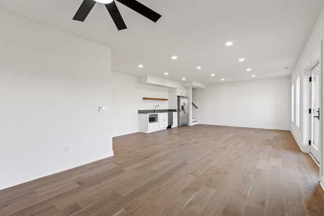 unfurnished living room featuring ceiling fan and light hardwood / wood-style flooring