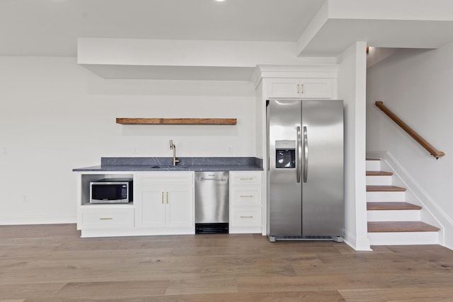 kitchen with stainless steel appliances, sink, wood-type flooring, and white cabinets