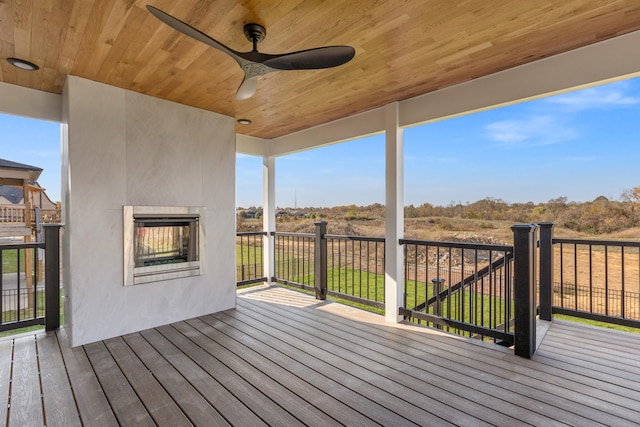 deck featuring ceiling fan and a multi sided fireplace