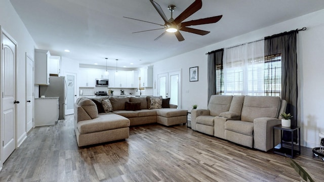 living room with sink, light hardwood / wood-style flooring, and ceiling fan