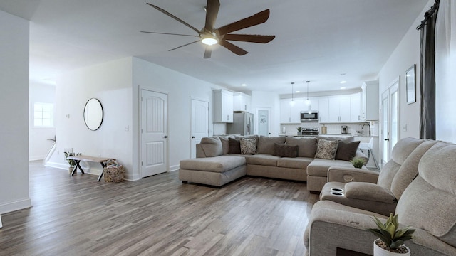 living room featuring sink, light hardwood / wood-style flooring, and ceiling fan