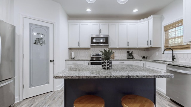 kitchen featuring sink, white cabinetry, stainless steel appliances, light stone countertops, and decorative backsplash