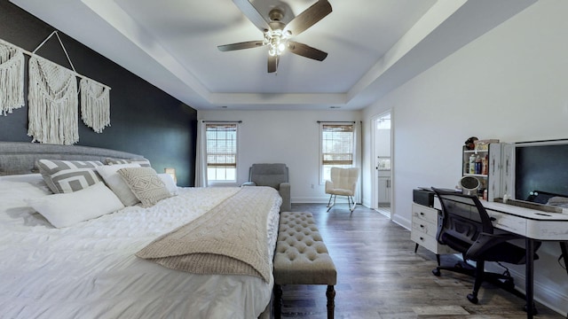 bedroom featuring dark hardwood / wood-style flooring, a tray ceiling, and ceiling fan