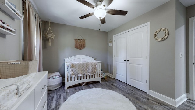 bedroom featuring dark hardwood / wood-style flooring, a nursery area, a closet, and ceiling fan