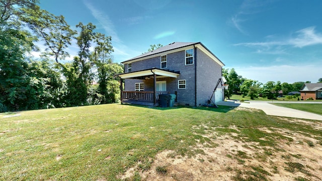 back of house featuring a garage, a yard, and covered porch