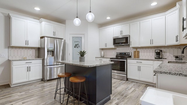 kitchen with white cabinetry, stainless steel appliances, a kitchen island, and pendant lighting