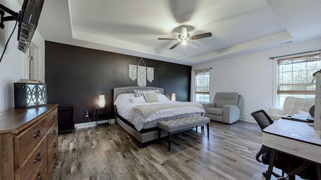 bedroom featuring a raised ceiling, hardwood / wood-style flooring, and ceiling fan