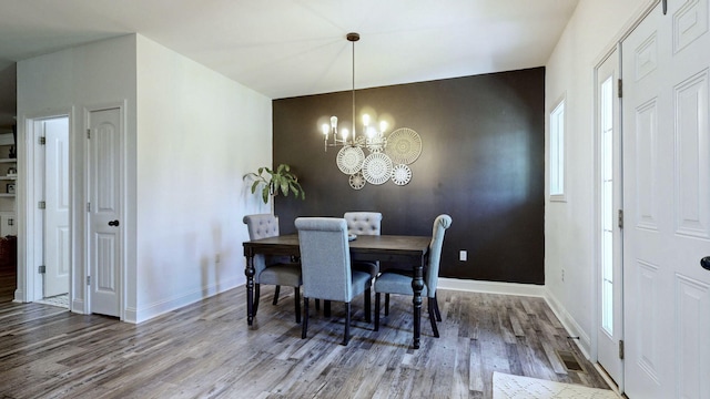 dining area with hardwood / wood-style floors and a chandelier