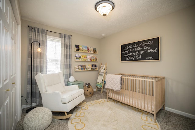 carpeted bedroom featuring a crib and a textured ceiling