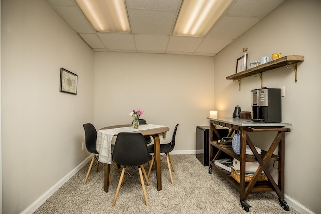 carpeted dining space with a drop ceiling