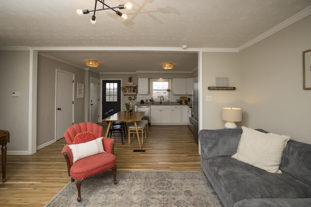 living room with ornamental molding, sink, light hardwood / wood-style flooring, and a textured ceiling