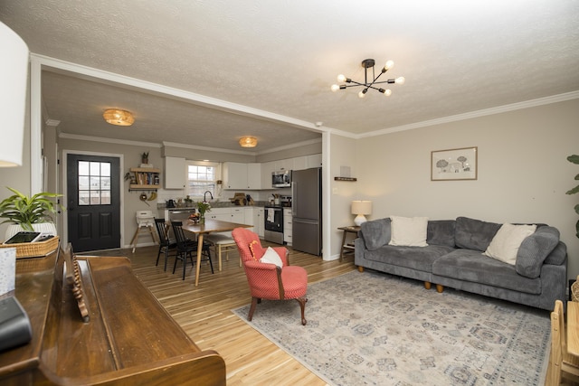 living room with ornamental molding, a chandelier, and light hardwood / wood-style flooring