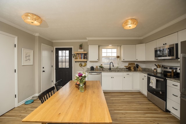 kitchen featuring sink, light hardwood / wood-style flooring, appliances with stainless steel finishes, light stone countertops, and white cabinets