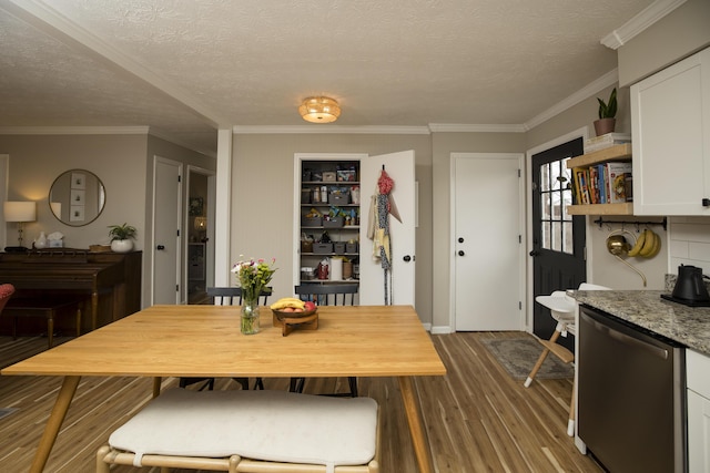 dining area featuring dark wood-type flooring, crown molding, and a textured ceiling