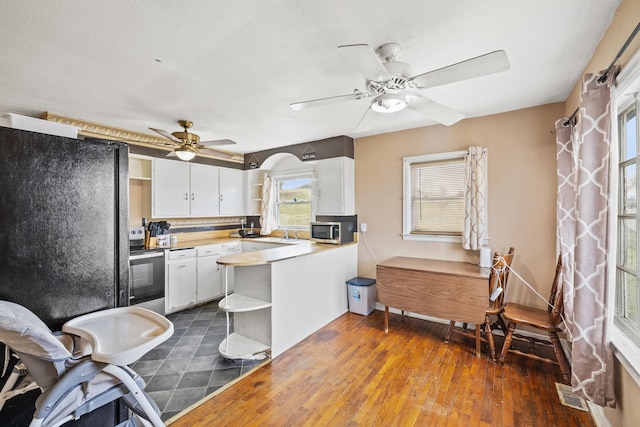 kitchen featuring appliances with stainless steel finishes, dark hardwood / wood-style floors, white cabinetry, ceiling fan, and kitchen peninsula